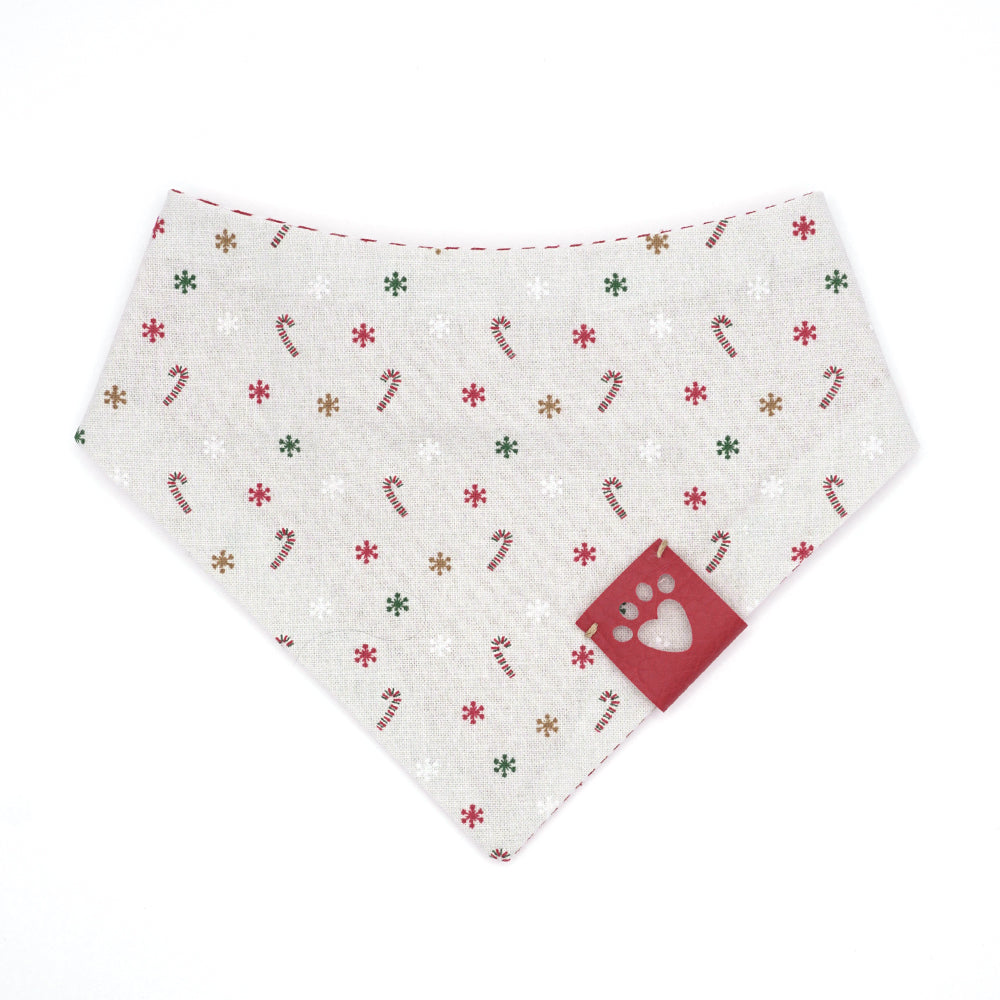 Reversible bandana for dogs. Snaps on back make it adjustable. One side is Light grey (almost white) background with red/white candy canes, and red, green, gold and white snowflakes and the other side has Red and white stripes. Red tag with heart paw cut out on side.