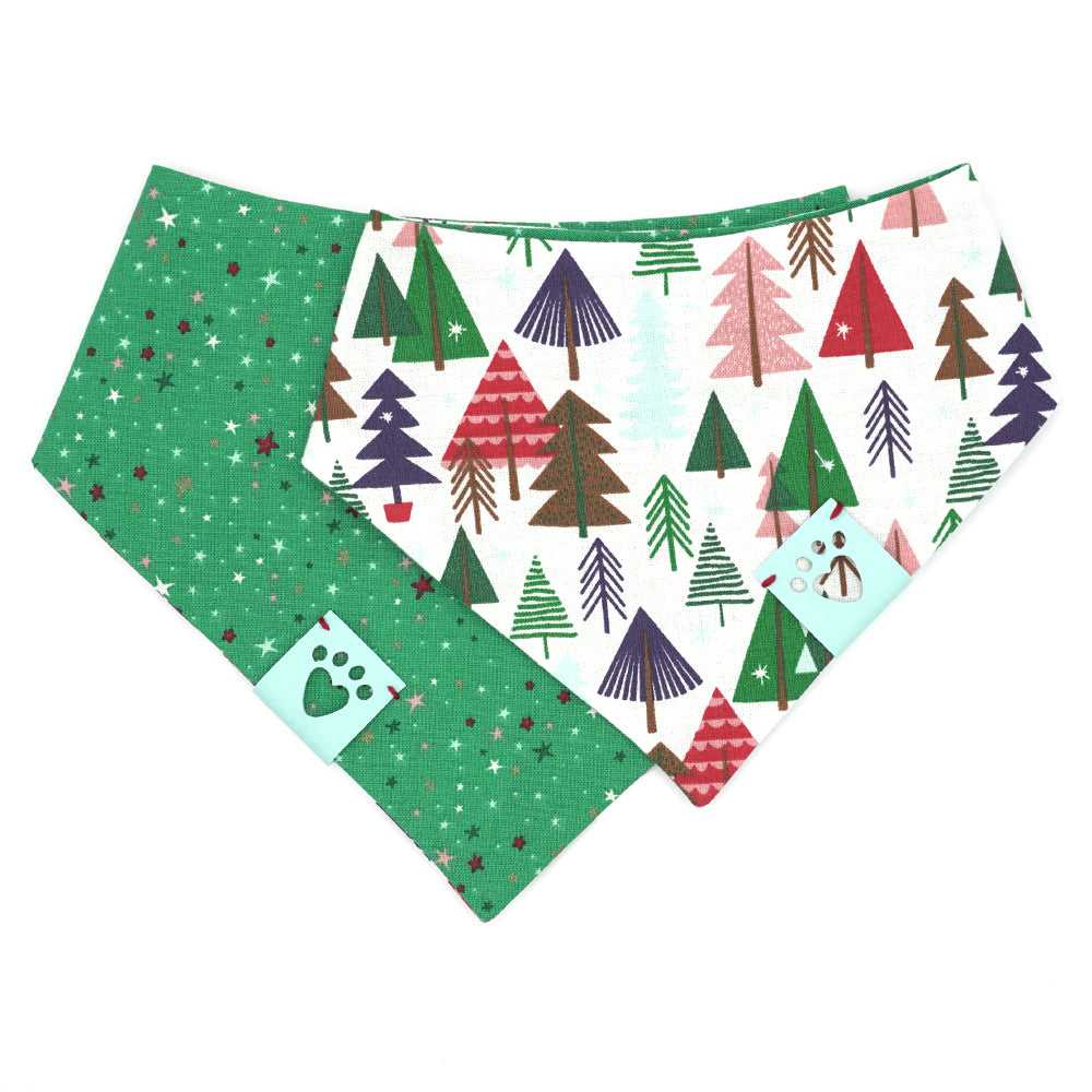 Reversible bandana for dogs. Snaps on back make it adjustable. One side is White background with illustrated trees in red, green, light blue, navy blue and brown and the other side has a Kelly green background with white, red, pink, light blue, dark green and navy blue stars. Light blue tag with heart paw cut out on side.