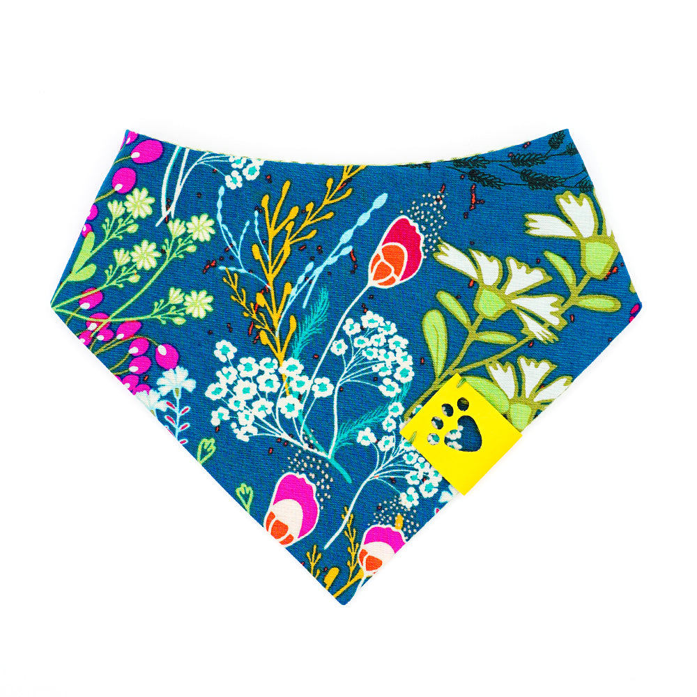 Reversible bandana for dogs. Snaps on back make it adjustable. One side is Dark green/teal background with magenta, dark purple, lime green, white, light blue, goldenrod, and orange flowers and the other side has a Bright lime green and white gingham pattern. Yellow tag with heart paw cut out on side.