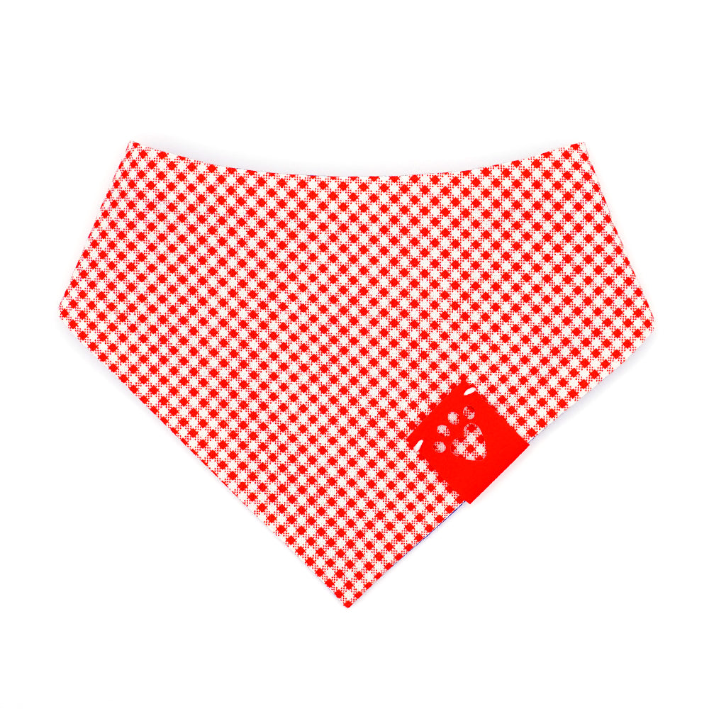 Reversible bandana for dogs. Snaps on back make it adjustable. One side is Medium blue background with a pattern of white dots and the other side has a Red and white gingham. Red tag with heart paw cut out on side.