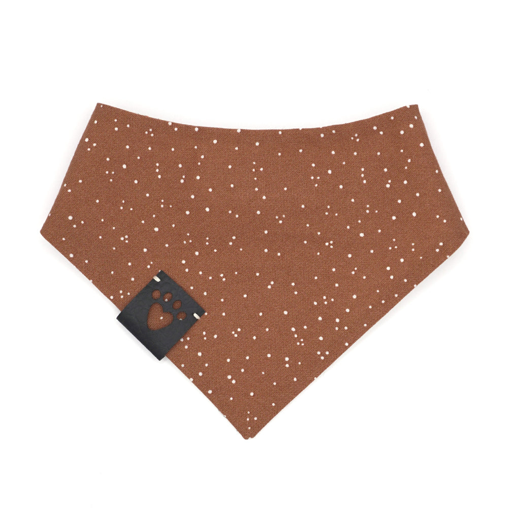 Reversible bandana for dogs. Snaps on back make it adjustable. One side is Light cream background with drawn snowman heads and orange carrot noses and the other side has a Pumpkin orange background with white "snow" dots. Black tag with heart paw cut out on side.