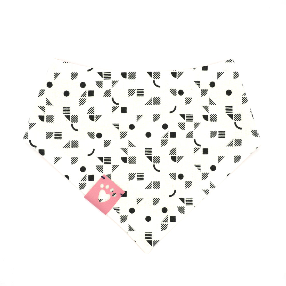 Reversible bandana for dogs. Snaps on back make it adjustable. One side is Bright orange background with newsprint boats and the other side has a White background with black geometric pattern. Light Pink tag with heart paw cut out on side.
