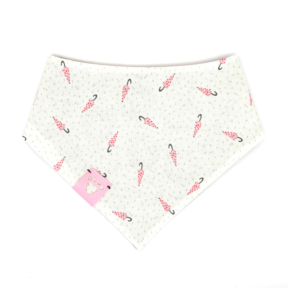 Reversible bandana for dogs. Snaps on back make it adjustable. One side is White background with pink polk-a-dot umbrellas and grey dots and the other side has a Charcoal grey background with black and pink flowers. Light pink tag with heart paw cut out on side.