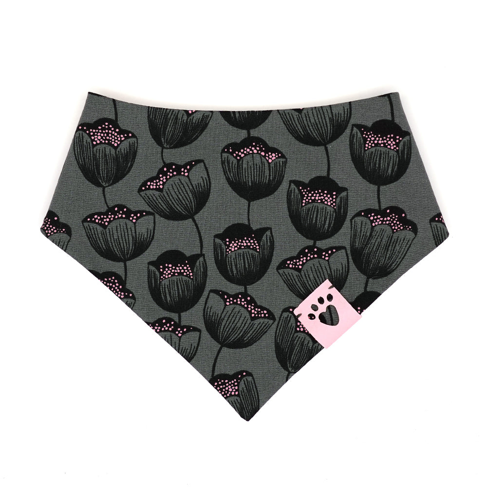 Reversible bandana for dogs. Snaps on back make it adjustable. One side is White background with pink polk-a-dot umbrellas and grey dots and the other side has a Charcoal grey background with black and pink flowers. Light pink tag with heart paw cut out on side.