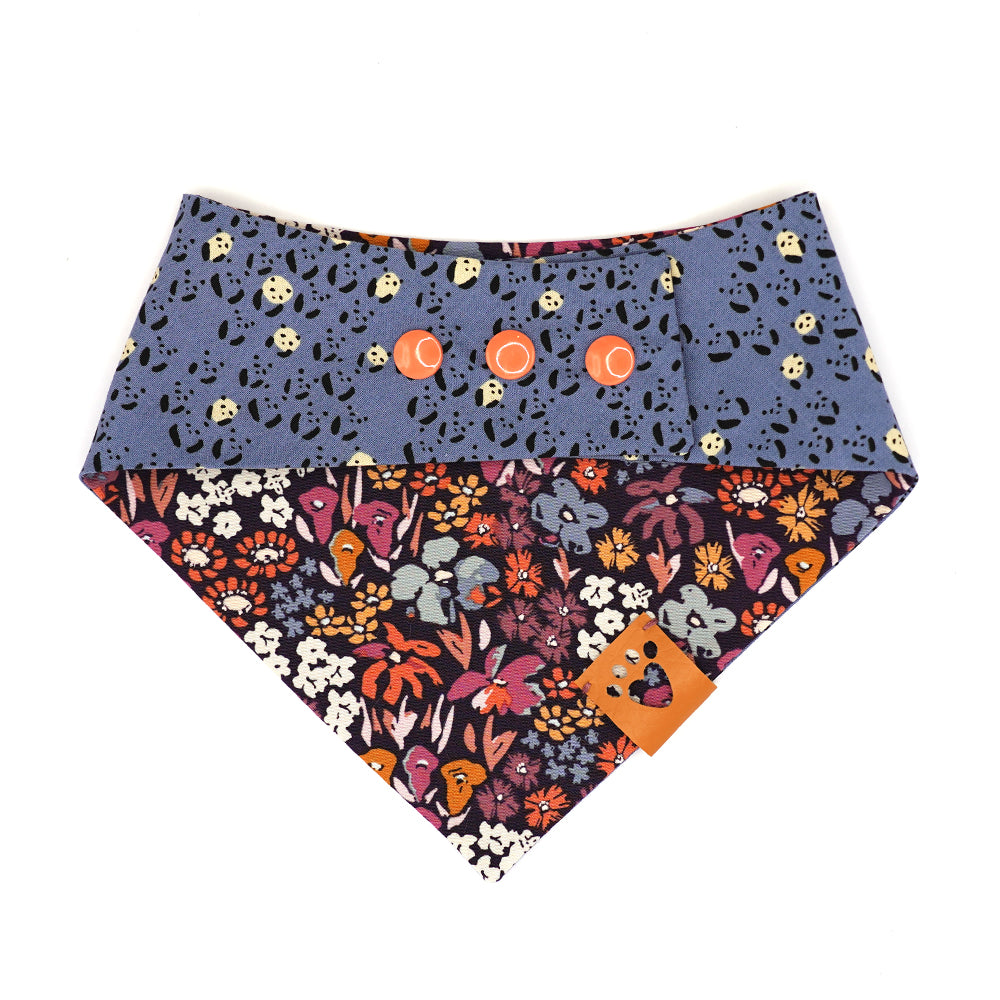 Reversible bandana for dogs. Snaps on back make it adjustable. One side is Periwinkle blue background with mini black and white pandas and the other side has a Dark purple background with coral, pink, cream, gold, orange and periwinkle flowers. Tan tag with heart paw cut out on side.