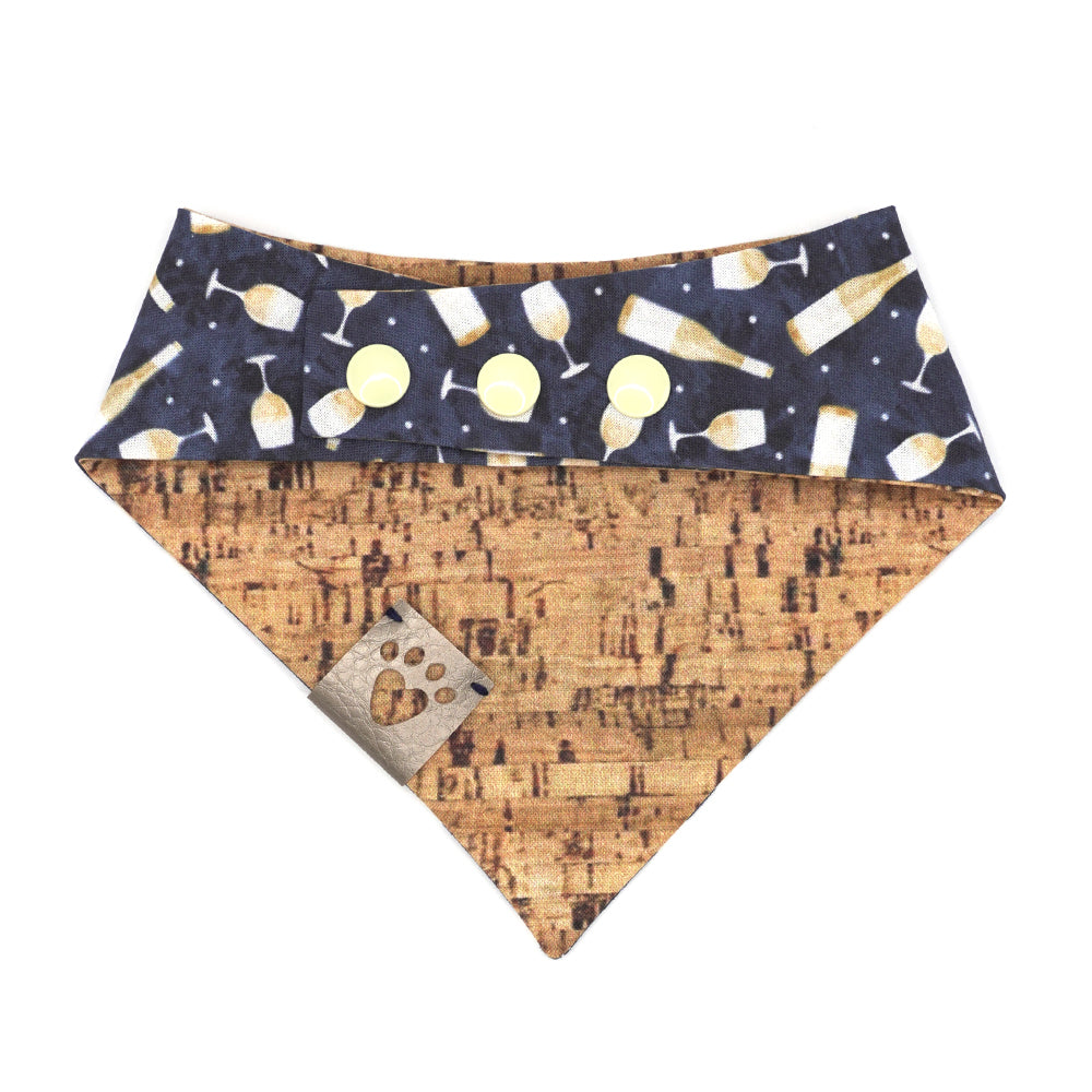 Reversible bandana for dogs. Snaps on back make it adjustable. One side is Navy blue background with white wine bottles and glasses and the other side has a Tan/brown cork pattern. Metallic Silver tag with heart paw cut out on side.
