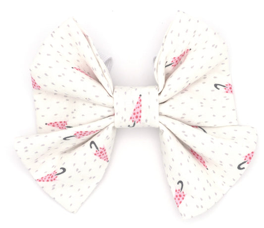 -Handmade cotton bow tie with tails for dogs (or other pets). Elastic straps on back with snaps make it easy to add to collar, harness, or leash. White background with pink polk-a-dot umbrellas and grey dots.