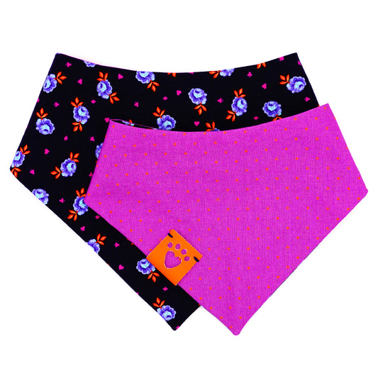 Reversible bandana for dogs. Snaps on back make it adjustable. One side is Navy blue background with purple and light blue rose buds, bright orange leaves and bright purple accent shapes and the other side has Bright purple background with bright orange dots. Orange tag with heart paw cut out on side.