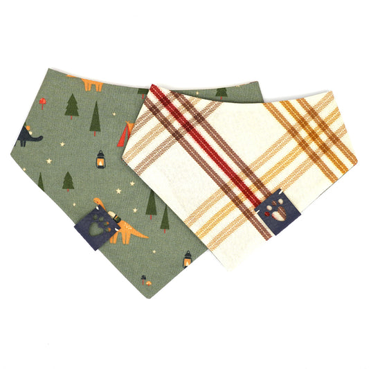 Reversible bandana for dogs. Snaps on back make it adjustable. One side is Army green background with tan, navy and orange dinos, tents, trees, lanterns and mushrooms and the other side has a Cream background with navy, forrest green, gold, red and brown plaid stripes. Navy tag with heart paw cut out on side.