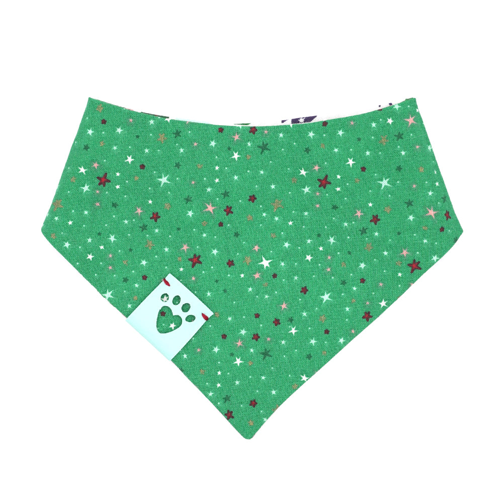 Reversible bandana for dogs. Snaps on back make it adjustable. One side is White background with illustrated trees in red, green, light blue, navy blue and brown and the other side has a Kelly green background with white, red, pink, light blue, dark green and navy blue stars. Light blue tag with heart paw cut out on side.