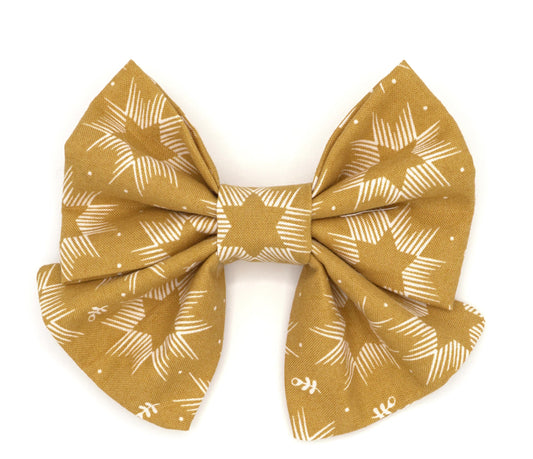 Handmade cotton bow tie with tails for dogs (or other pets). Elastic straps on back with snaps make it easy to add to collar, harness, or leash. Mustard yellow background with cream Stars of David.
