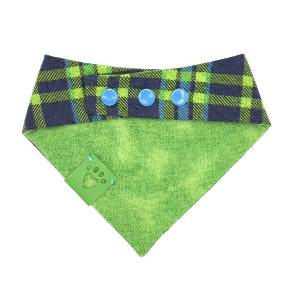 Reversible bandana for dogs. Snaps on back make it adjustable. One side is Bright blue, navy blue and bright green plaid and the other side has a Bright green print that looks like a golf green. Green tag with heart paw cut out on side.