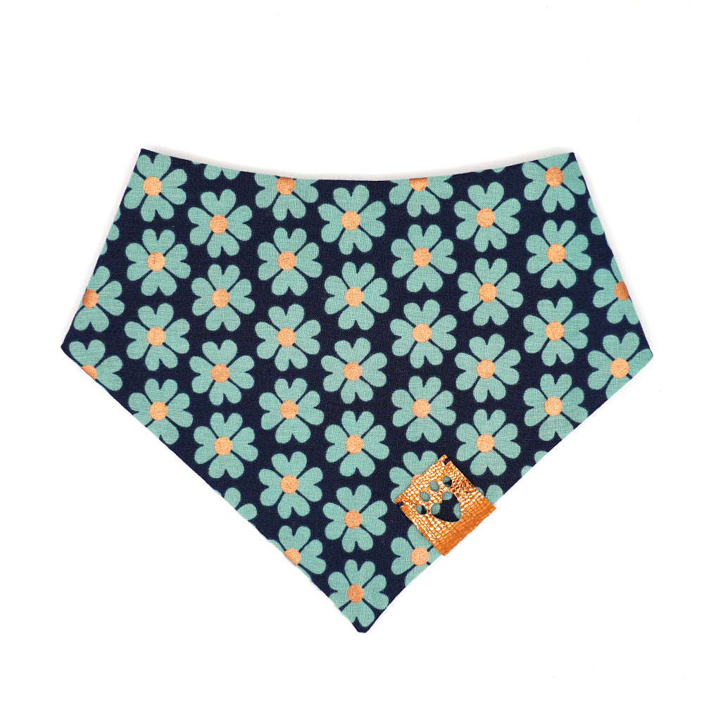 Reversible bandana for dogs. Snaps on back make it adjustable. One side is White and green/blue gingham stripes and the other side has a Navy background with green/blue flowers that have metallic copper centers. Metallic copper tag with heart paw cut out on side.