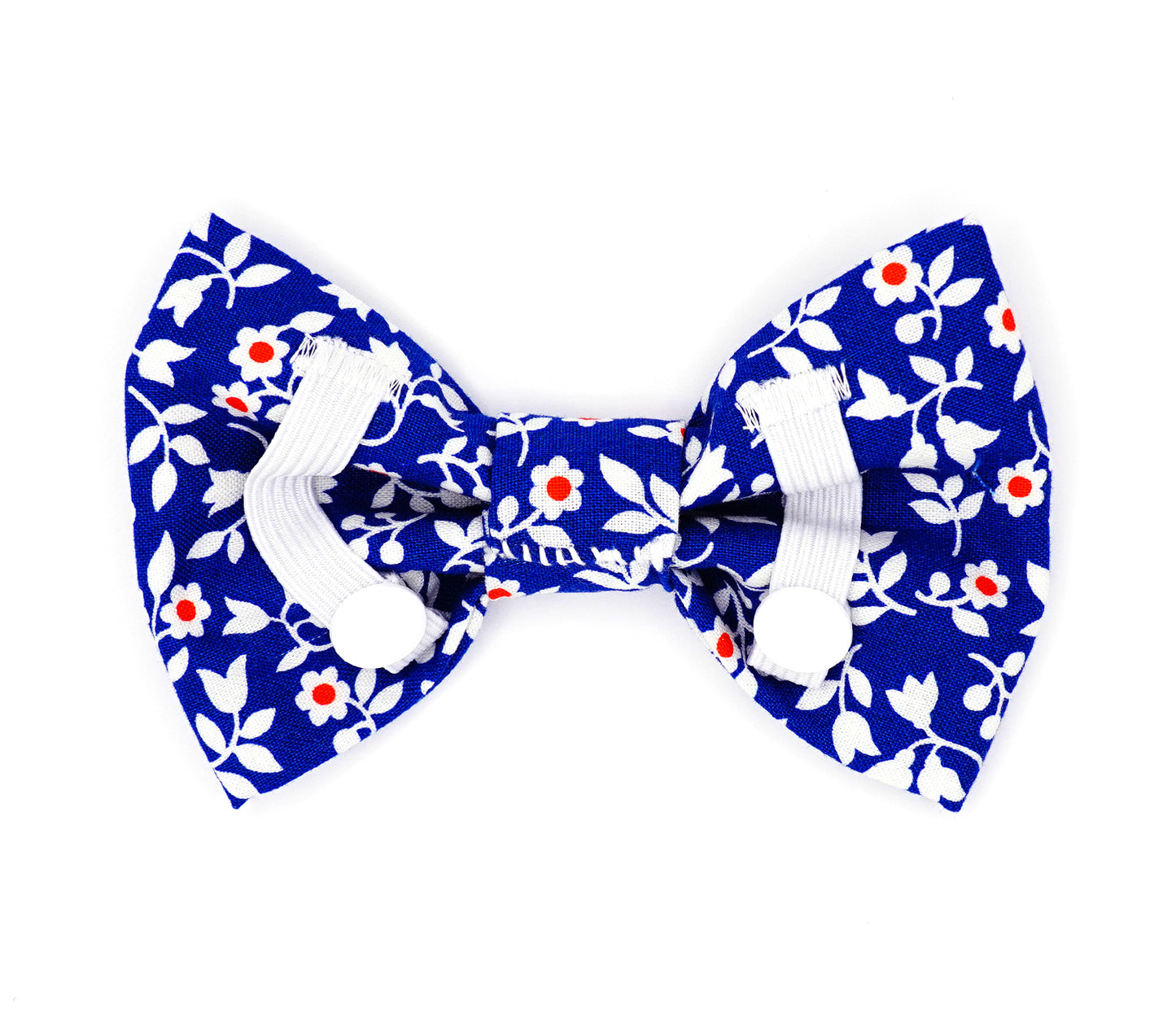 Handmade cotton bow tie for dogs (or other pets). Elastic straps on back with snaps make it easy to add to collar, harness, or leash. Medium blue background with red and white flowers.