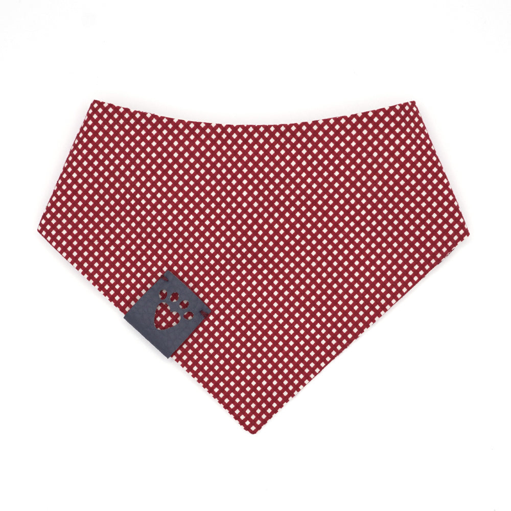 Reversible bandana for dogs. Snaps on back make it adjustable. One side is White background with dark red vintage Santa heads and the other side has a Dark red and white micro gingham. Navy tag with heart paw cut out on side.