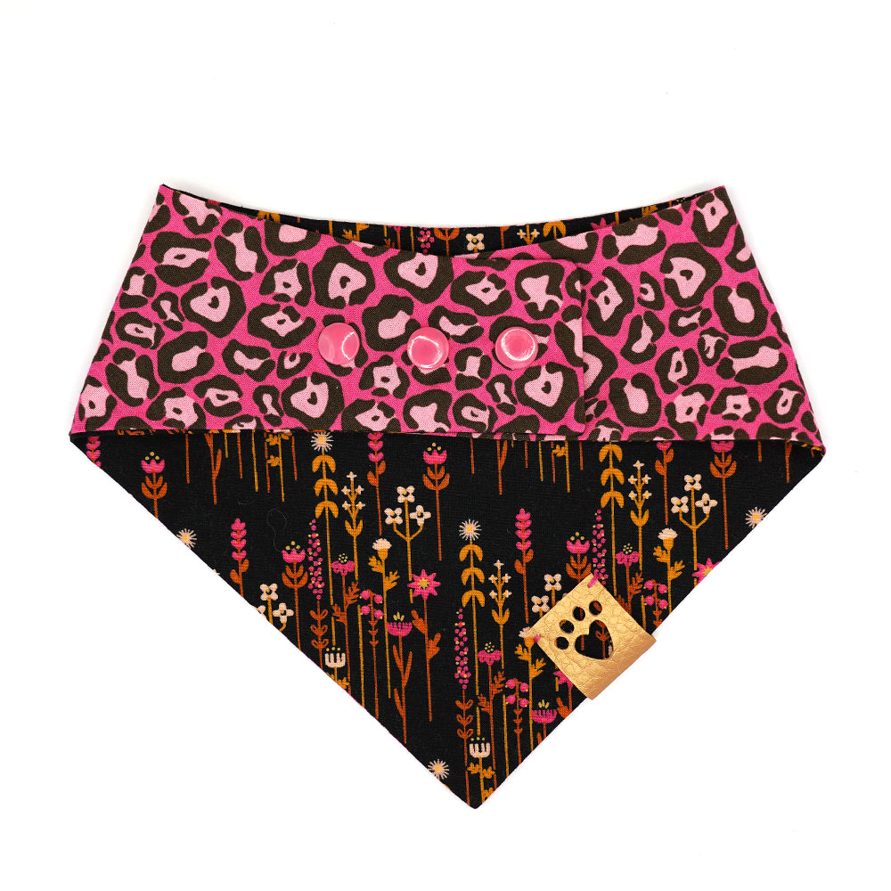Reversible bandana for dogs. Snaps on back make it adjustable. One side is Hot pink background with light pink and charcoal grey leopard print and the other side has a Black background with hot pink, amber, gold and cream flowers. Metallic gold tag with heart paw cut out on side.