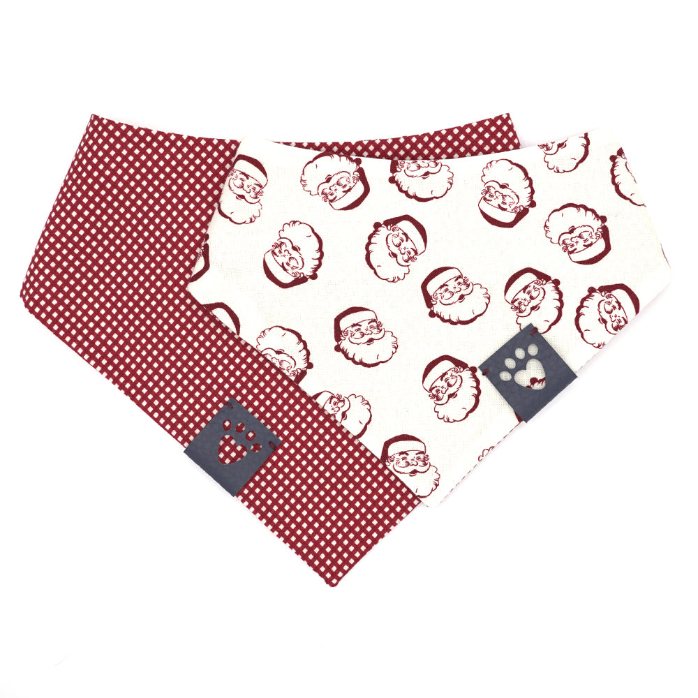 Reversible bandana for dogs. Snaps on back make it adjustable. One side is White background with dark red vintage Santa heads and the other side has a Dark red and white micro gingham. Navy tag with heart paw cut out on side.