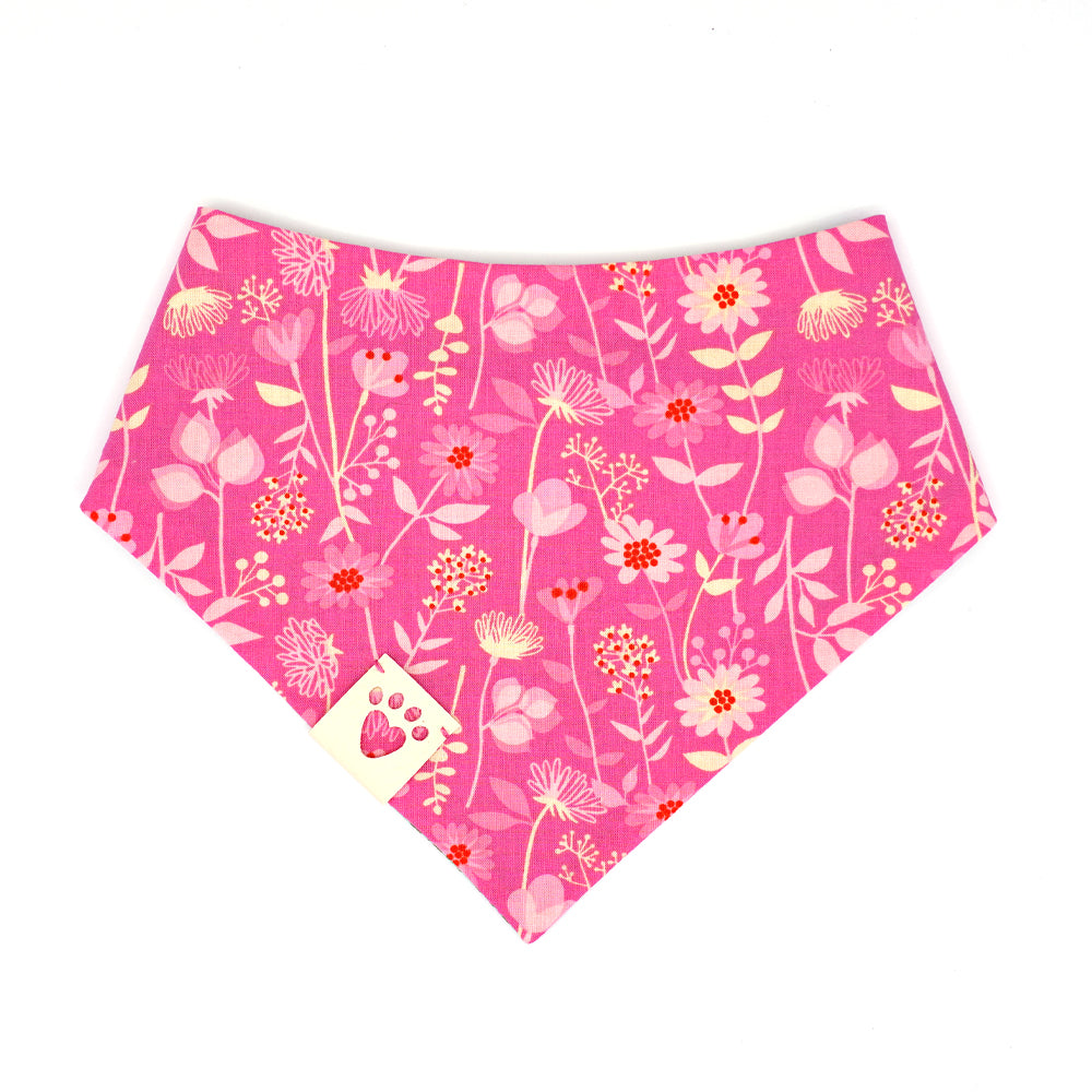  Reversible bandana for dogs. Snaps on back make it adjustable. One side is Teal green background with pink safety pins and dark green flowers and the other side has a Bright pink background with pink, cream and red flowers. Cream tag with heart paw cut out on side.