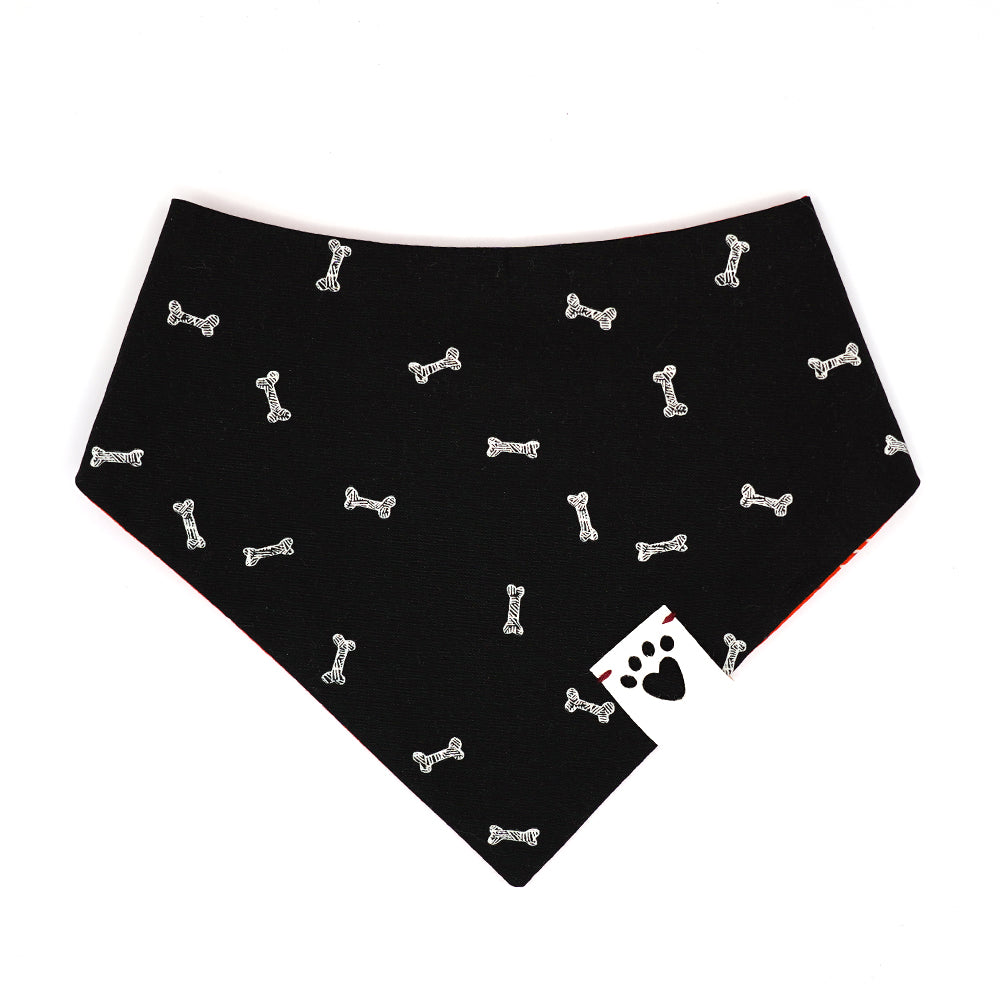 Reversible bandana for dogs. Snaps on back make it adjustable. One side is Black background with white illustrated dog bones and the other side has a Red/orange background with black and white strawberry seeds pattern. White tag with heart paw cut out on side.