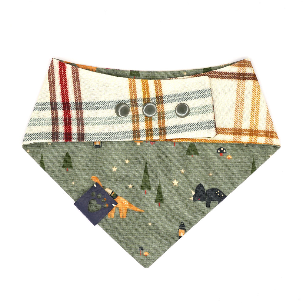 Reversible bandana for dogs. Snaps on back make it adjustable. One side is Army green background with tan, navy and orange dinos, tents, trees, lanterns and mushrooms and the other side has a Cream background with navy, forrest green, gold, red and brown plaid stripes. Navy tag with heart paw cut out on side.