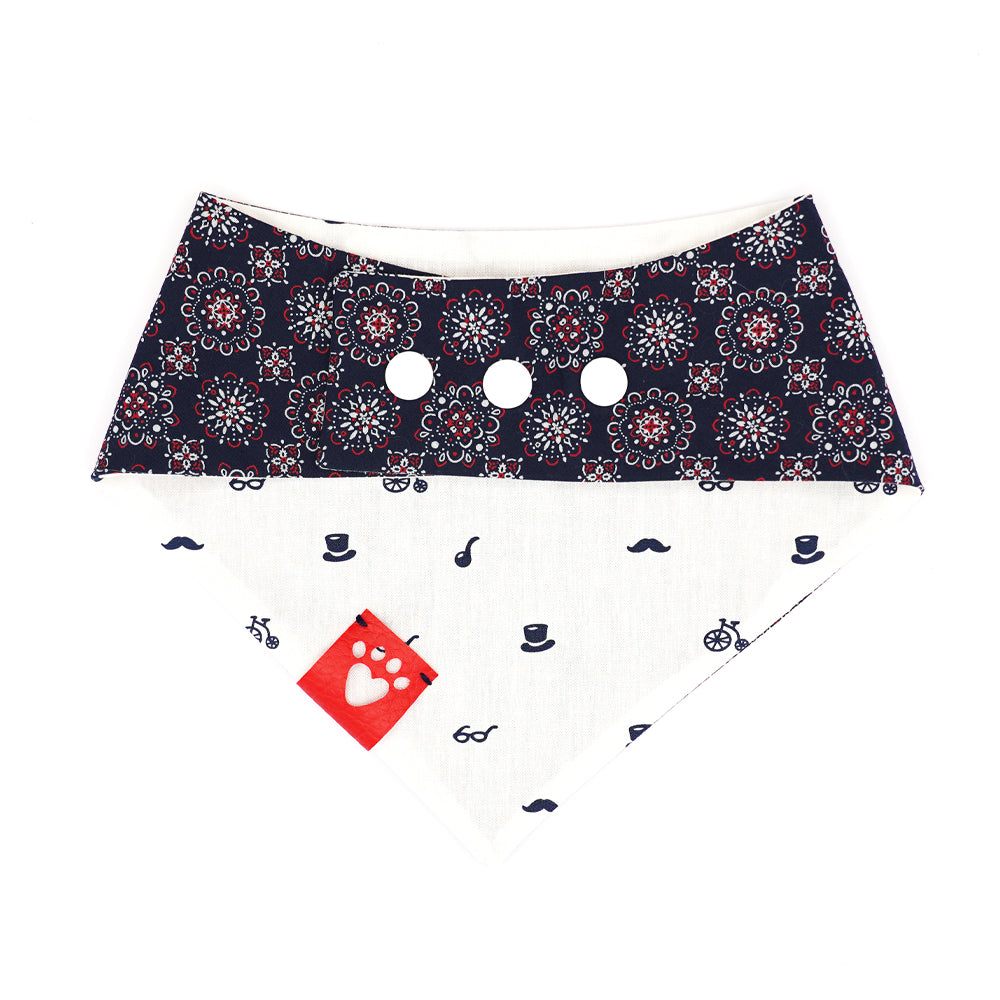 Reversible bandana for dogs. Snaps on back make it adjustable. One side is White background with navy blue glasses, top hats, pipes, mustaches and high wheeler bikes and the other side has a Navy blue background with red and white mandalas. Red tag with heart paw cut out on side.
