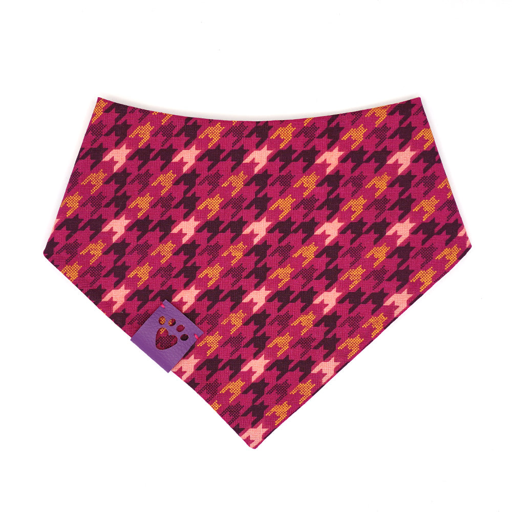 Reversible bandana for dogs. Snaps on back make it adjustable. One side is Pink background with gold, maroon and light pink houndstooth pattern and the other side has a Cream background with geometric shaped butterflies in light pink, gold, maroon, purple and navy. Purple tag with heart paw cut out on side.