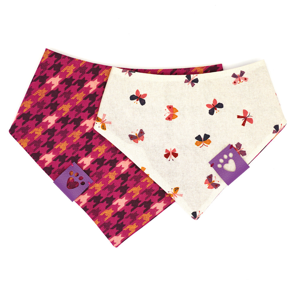Reversible bandana for dogs. Snaps on back make it adjustable. One side is Pink background with gold, maroon and light pink houndstooth pattern and the other side has a Cream background with geometric shaped butterflies in light pink, gold, maroon, purple and navy. Purple tag with heart paw cut out on side.