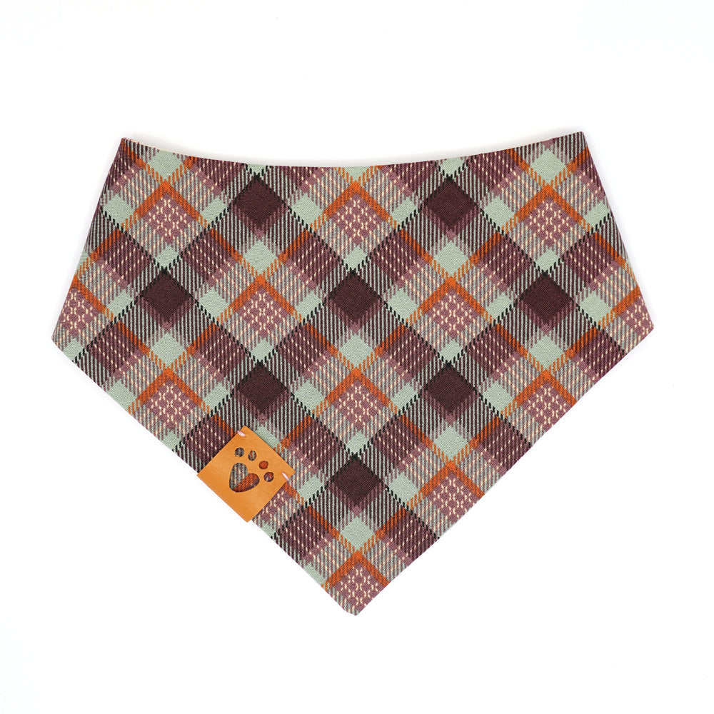 Reversible bandana for dogs. Snaps on back make it adjustable. One side is Beige background with two bunnies, the sun, butterflies and florals in goldenrod, purple, lilac, orange, seafoam green and peach and the other side has a Purple, lavender, orange, peach and seafoam green plaid. Tan tag with heart paw cut out on side.