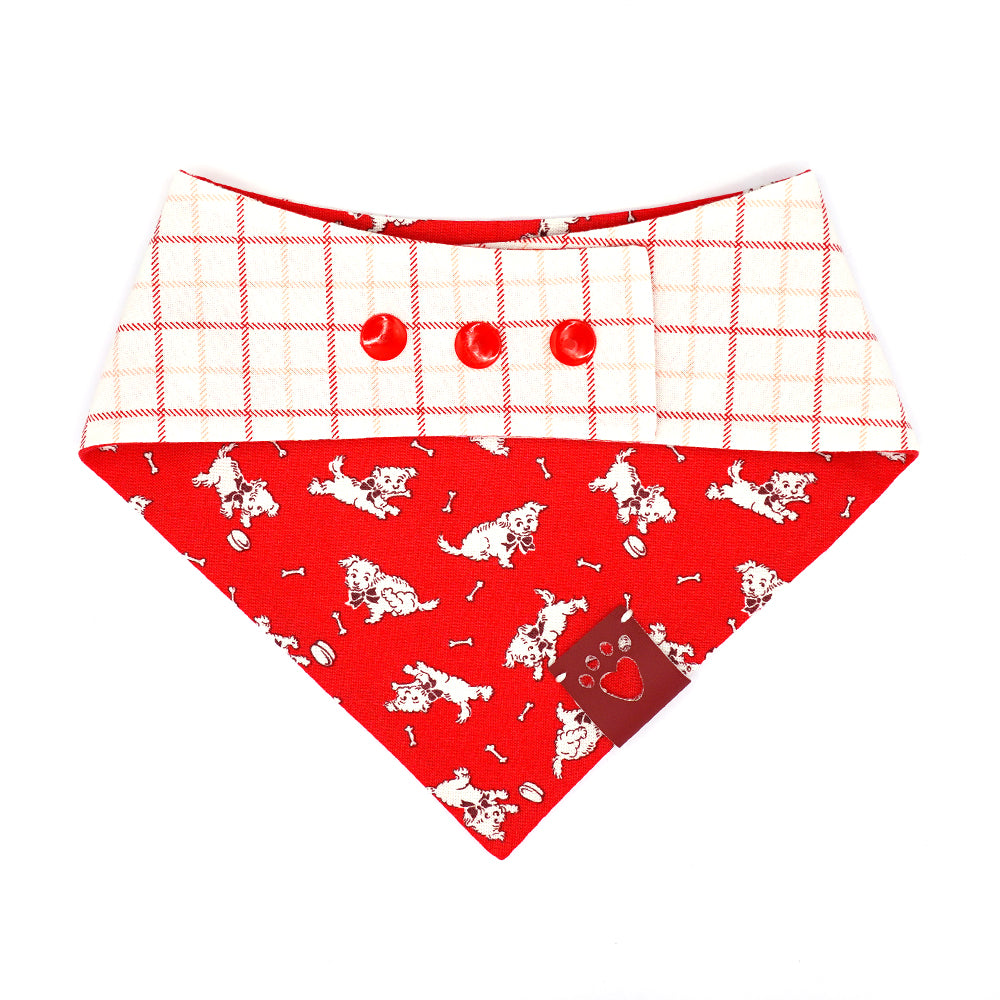 Reversible bandana for dogs. Snaps on back make it adjustable. One side is Bright red background with playful, white, vintage  puppies and the other side has a White background with red and pink line plaid. Dark red tag with heart paw cut out on side.